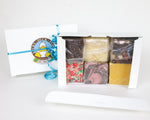 2 large boxes of fudge by Lucky Duck Fudge. One box is gift wrapped with a blue, curled ribbon, and the other box is open to show 6 cubes of different flavours of fudge.